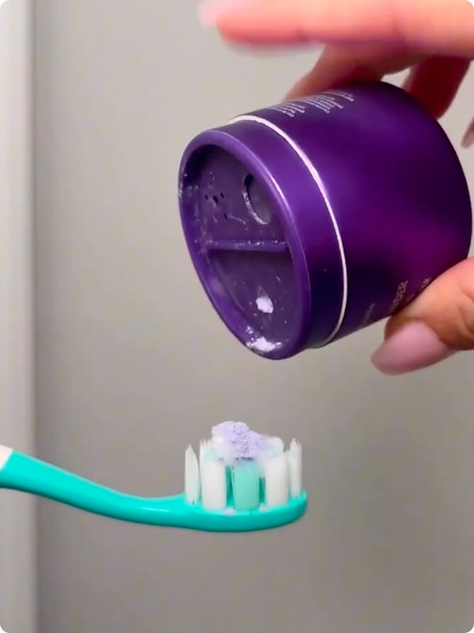 Sprinkling the purple powder onto a toothbrush