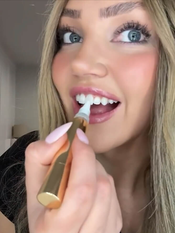 Woman brushing the whitening serum onto her teeth